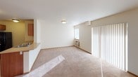 Located at 901 Sunburst Ct, Unit H105 in Moses Lake, Washington, this single-floor unit offers a practical and comfortable layout designed for everyday living. The open living area is finished with neutral wall-to-wall carpeting and flush ceiling lighting, creating a bright and clean atmosphere. A peninsula counter seamlessly connects the living space to the kitchen, providing a convenient pass-through and casual dining surface. Natural light filters in through a window and a sliding glass door dressed with vertical blinds, while a wall-mounted air conditioning unit ensures year-round comfort. The kitchen is well-appointed with warm honey-toned cabinetry offering ample storage, light laminate countertops, and a full suite of black appliances including a range, microwave, refrigerator, and a stainless steel sink. Tile flooring runs throughout the kitchen for easy maintenance. The bedroom is a comfortable retreat, featuring plush carpeting, a ceiling fan with light fixture, a baseboard heater, and a window with blinds for natural light and privacy. The bathroom includes a wood-toned vanity with countertop, tile flooring, a baseboard heater, and essential fixtures. An in-unit laundry area adds further convenience to this well-organized living space.