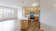 Located at 808 Berry St in Saint Paul, MN, this 2-bedroom, 1-bathroom unit offers a well-designed, single-floor layout that maximizes everyday functionality. The open-concept kitchen and living area serves as the heart of the home, featuring warm honey-toned cabinetry, stainless steel appliances including a range, microwave, and refrigerator, and a peninsula with a built-in sink and pendant lighting above — ideal for casual dining or meal prep. Wood-look plank flooring flows throughout the main living areas, lending a cohesive and clean aesthetic. A standout corner fireplace with a sleek black and gold surround adds warmth and character to the living space. Large windows with vertical blinds invite generous natural light into both the living area and the bedrooms. The bedrooms are carpeted for comfort, with the primary bedroom offering a walk-in closet equipped with built-in shelving. The full bathroom includes a soaking tub and shower combo with clean white finishes and wood-look flooring. Hallways connect the rooms efficiently, and the overall neutral palette throughout creates a bright, move-in-ready atmosphere suited for a range of lifestyles.