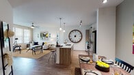 This single-floor residence offers a thoughtfully designed open-concept layout that seamlessly connects the kitchen, dining, and living areas. The kitchen is equipped with stainless steel appliances, light wood cabinetry, a subway tile backsplash, and a central island with white countertops that doubles as a breakfast bar. Track lighting and pendant lights illuminate the space, while wood-look flooring flows throughout the main living areas. The dining area is a defined nook highlighted by recessed accent lighting and direct access to the entry, providing an intimate setting for meals. The living room is bright and airy, featuring large windows with blinds and sheer curtains, a ceiling fan, and a glass door that invites natural light and outdoor access. Two bedrooms offer comfortable retreats, each with ceiling fans, plush carpet, and generous window coverage for natural light. The primary bathroom includes a walk-in glass-enclosed shower and wood-look flooring, while the secondary bathroom features a full soaking tub and shower combo with a modern vanity and ample storage. A dedicated in-unit laundry room with a full-size washer and dryer, overhead shelving, and hanging storage adds everyday convenience to this well-rounded residence.