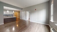 This well-appointed one-bedroom, one-bathroom unit at 4328 Ridge Ave in Philadelphia's East Falls neighborhood offers a thoughtfully designed open-concept layout. The combined kitchen and living area forms the heart of the home, featuring durable hardwood-style flooring that flows seamlessly throughout. The modern kitchen is equipped with stainless steel appliances, including an electric range, microwave, and refrigerator, complemented by sleek dark cabinetry with gold-tone hardware, white quartz countertops, a tile backsplash, and a peninsula with additional prep and storage space. A pendant light adds a refined touch overhead. The spacious living area receives generous natural light through large windows with views of the surrounding neighborhood, and includes a wall-mounted HVAC unit for year-round comfort. The bedroom offers plush carpeting, a double-door closet, and its own large window allowing ample daylight. The full bathroom features light-toned tile flooring, a floating dark-wood vanity with a white sink, a tub-shower combination, and a large mirror. Neutral gray tones are carried throughout the unit, creating a clean, contemporary aesthetic that is both inviting and functional.