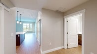 Located at 111 W Lamme Street in the heart of Bozeman, Montana, this well-appointed one-bedroom, two-bathroom unit offers a thoughtfully designed single-level layout. The open-concept kitchen and living area serves as the centerpiece of the home, featuring rich medium-toned shaker cabinetry, quartz countertops, a classic white subway tile backsplash, stainless steel appliances, and light hardwood-style flooring that flows throughout the main living spaces. Large windows in the living area flood the space with natural light and provide views of the surrounding Bozeman streetscape and greenery. The bedroom offers a comfortable footprint with plush carpet, dual windows with mountain views, and direct access to a spacious walk-in closet lined with wire shelving on both sides. The primary bathroom is finished with warm wood cabinetry, quartz counters, and a sleek sliding glass walk-in shower with white tile surround. A second full bathroom mirrors the same clean, modern aesthetic. Neutral warm-gray walls, recessed lighting, and clean white trim are consistent throughout, creating a cohesive and contemporary ambiance. The layout also includes a hallway with built-in storage access, adding to the overall functionality of the space.