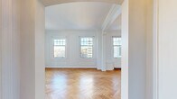 Located at 925 E Wells St in Milwaukee's vibrant East Town neighborhood, this 2-bedroom, 2-bathroom residence blends classic architectural character with functional design. Throughout the living areas and bedrooms, warm herringbone-patterned hardwood floors create a timeless aesthetic, complemented by crisp white walls, decorative panel moldings, and elegant crown molding details. Arched doorways and columned transitions add architectural interest as spaces flow from one room to the next.

The two living areas are bright and generously scaled, with large multi-pane windows framing elevated views of the Milwaukee skyline and filling the rooms with natural light. The spacious primary bedroom continues the herringbone flooring and offers ample closet access, while the second bedroom also enjoys city views through its sizable window.

The kitchen is efficiently designed with stainless steel appliances — including a gas range, microwave, and refrigerator — white cabinetry, a subway tile backsplash, and light tile flooring. Two distinct bathrooms provide variety: one features classic white subway tile, a pedestal sink, hexagonal mosaic floor tile, and a soaking tub, while the second offers a retro-styled design with mint green fixtures and matching penny tile flooring. Together, these spaces create a characterful and well-appointed urban residence.
