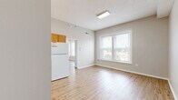 Located at 121 W Poplar St in Sidney, Ohio, this efficient one-bedroom, one-bathroom unit offers a well-organized single-floor layout designed to maximize every square foot. Light-toned hardwood-style flooring runs throughout the main living areas and bedroom, lending a clean, cohesive aesthetic across the space.

The kitchen is a standout feature, configured in an L-shaped layout with warm oak cabinetry extending to the upper walls, offering generous storage capacity. White appliances — including an electric range, refrigerator, and under-cabinet range hood — provide all essential cooking amenities, while light countertops complement the cabinetry's natural tones.

The bedroom is a comfortable, well-proportioned room featuring large double windows fitted with horizontal blinds, allowing natural light to fill the space while offering views of the surrounding streetscape. A closet with a full-panel door provides convenient storage.

The bathroom is finished with rich, dark hardwood-style flooring, creating a warm contrast to the white walls and fixtures. It includes a full soaking tub with shower, a toilet, and overhead lighting. A dedicated entrance area connects the rooms, completing a practical and functional floor plan suited for comfortable everyday living in the heart of Sidney, Ohio.