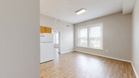 Located at 121 W Poplar St in Sidney, Ohio, this efficient one-bedroom, one-bathroom unit offers a well-organized single-floor layout designed to maximize every square foot. Light-toned hardwood-style flooring runs throughout the main living areas and bedroom, lending a clean, cohesive aesthetic across the space.

The kitchen is a standout feature, configured in an L-shaped layout with warm oak cabinetry extending to the upper walls, offering generous storage capacity. White appliances — including an electric range, refrigerator, and under-cabinet range hood — provide all essential cooking amenities, while light countertops complement the cabinetry's natural tones.

The bedroom is a comfortable, well-proportioned room featuring large double windows fitted with horizontal blinds, allowing natural light to fill the space while offering views of the surrounding streetscape. A closet with a full-panel door provides convenient storage.

The bathroom is finished with rich, dark hardwood-style flooring, creating a warm contrast to the white walls and fixtures. It includes a full soaking tub with shower, a toilet, and overhead lighting. A dedicated entrance area connects the rooms, completing a practical and functional floor plan suited for comfortable everyday living in the heart of Sidney, Ohio.