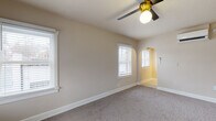 Located at 225 S 400 E in Salt Lake City, Utah, this single-floor residence blends classic architectural details with modern upgrades throughout. The living area features soft carpeting, neutral warm-toned walls, multiple windows with white blinds that invite natural light, a ceiling fan with a gold accent fixture, and a charming arched doorway that adds character to the space. The thoughtfully renovated kitchen is a standout, showcasing deep slate-blue shaker-style cabinetry paired with striking granite countertops, a white subway tile backsplash, brushed gold hardware and faucet, and a full suite of stainless steel appliances including a gas range, dishwasher, and over-the-range microwave. The bedrooms continue the warm, neutral palette with plush carpeting and ample natural light provided by white-trimmed windows. Ceiling fans with gold fixtures are featured in multiple rooms, maintaining a cohesive design language throughout. The bathroom is elegantly appointed with white subway tile surrounding a soaking tub, marble-look tile flooring, a pedestal sink, and gold fixtures that tie together the home's consistent accent theme. The overall ambiance is clean, bright, and move-in ready, with a well-considered balance of classic detailing and contemporary finishes.