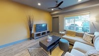 Located at 760 North Central Avenue in Moses Lake, Washington, this modern single-floor unit offers a well-designed layout with multiple bedrooms, a functional open-concept living and kitchen area, and contemporary finishes throughout. The kitchen is thoughtfully appointed with white cabinetry, dark countertops, full-sized black appliances including a refrigerator, dishwasher, range, and microwave, along with a double basin sink and open display shelving. A central island with pendant lighting doubles as a dining bar, seamlessly connecting the kitchen to the living space. The living area features wood-look plank flooring, a ceiling fan, recessed lighting, and a bold yellow accent wall that adds a vibrant pop of color. Large windows allow natural light to flow in and provide views of the surrounding neighborhood. The bedrooms are comfortably sized, each featuring patterned carpet, ceiling fans, and windows with exterior views. The bathrooms are finished with white vanity cabinetry, gray countertops, and a walk-in shower. A shared hallway connects the private rooms to the common areas, maintaining a clean and functional flow throughout the unit. The overall design balances modern aesthetics with practical, everyday livability.