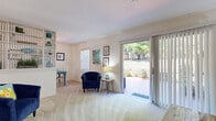 Located at 4513 Williamstown Blvd in Lakeland, Florida, this single-story, one-bedroom, one-bathroom home offers a well-organized layout across a comfortable footprint. The combined living and dining area forms the heart of the home, featuring soft carpeting, neutral walls, and an abundance of natural light. A large sliding glass door opens directly to a private outdoor patio, offering pleasant views of surrounding greenery and seamlessly connecting the interior to the outdoors. The living area provides ample room for seating and relaxation, while the adjacent dining space accommodates a full dining table, making it ideal for everyday meals or casual entertaining. A dedicated hallway connects the main living spaces to the private quarters, contributing to a logical and efficient flow throughout the home. The bedroom is generously sized, featuring carpeted floors, vaulted-style ceilings, and a reach-in closet with built-in shelving for convenient storage. The full bathroom is bright and clean, finished with tile flooring, a tub-shower combination, a single vanity with a large mirror, and a window that brings in natural light. Overall, the home presents a cohesive, coastal-inspired ambiance with a practical and comfortable layout suited for single occupancy or a couple.