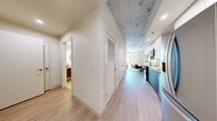 Located at 622 8th Ave S in Nashville's vibrant SoBro district, this one-bedroom, one-bathroom unit offers a thoughtfully designed single-floor layout with a modern industrial aesthetic. Light wood-tone flooring runs throughout, complementing the striking exposed concrete ceilings that lend an urban, loft-inspired character to the space.

The open-concept living and dining area is bright and inviting, with clean white walls and a relaxed, neutral palette. The space comfortably accommodates a seating area alongside a dining nook, creating a functional yet stylish everyday living environment.

The kitchen is a standout feature, equipped with two-tone cabinetry pairing white uppers with warm wood-grain lowers, quartz countertops, a white subway tile backsplash, stainless steel appliances including a refrigerator, range, and microwave, and gold-accented hardware for a refined finishing touch.

The generously sized primary bedroom offers a serene retreat with ample room for a full bedroom suite and includes a well-organized walk-in closet with built-in shelving and hanging storage.

The bathroom is finished to a high standard, featuring large-format marble-look porcelain tile on both the floors and shower walls, a glass-enclosed shower, a floating wood vanity, and clean, minimalist fixtures that complete the spa-like feel. A hallway with louvered closet doors provides additional storage near the entry.