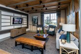 Located at 6038 Hixson Pike in Hixson, Tennessee, this single-story community clubhouse delivers a polished blend of rustic warmth and contemporary design. The welcoming lounge area anchors the space with soaring wood-paneled vaulted ceilings, exposed painted beams, and rich natural wood accent walls that create a striking focal point. Comfortable seating, curated artwork, and wood-look flooring throughout contribute to a cohesive, inviting ambiance.

The kitchen and social area features an expansive granite island with bar seating, pendant lighting, chevron-tile backsplash, wall-mounted TV, open shelving, and built-in appliances — ideal for gatherings. Adjacent high-top tables and casual seating areas offer additional space for socializing.

A dedicated co-working and conference zone includes a refined conference room with a wall-mounted TV, neutral furnishings, and frosted glass panels for privacy, alongside a built-in workspace with marble countertops, warm wood cabinetry, and barn door access to the main lounge.

The spacious fitness center is outfitted with cardio machines, strength equipment, free weights, stability balls, wall mirrors, large windows that flood the room with natural light, and ceiling fans beneath vaulted ceilings — providing an energizing environment for exercise.