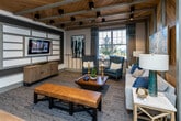 Located at 6038 Hixson Pike in Hixson, Tennessee, this single-story community clubhouse delivers a polished blend of rustic warmth and contemporary design. The welcoming lounge area anchors the space with soaring wood-paneled vaulted ceilings, exposed painted beams, and rich natural wood accent walls that create a striking focal point. Comfortable seating, curated artwork, and wood-look flooring throughout contribute to a cohesive, inviting ambiance.

The kitchen and social area features an expansive granite island with bar seating, pendant lighting, chevron-tile backsplash, wall-mounted TV, open shelving, and built-in appliances — ideal for gatherings. Adjacent high-top tables and casual seating areas offer additional space for socializing.

A dedicated co-working and conference zone includes a refined conference room with a wall-mounted TV, neutral furnishings, and frosted glass panels for privacy, alongside a built-in workspace with marble countertops, warm wood cabinetry, and barn door access to the main lounge.

The spacious fitness center is outfitted with cardio machines, strength equipment, free weights, stability balls, wall mirrors, large windows that flood the room with natural light, and ceiling fans beneath vaulted ceilings — providing an energizing environment for exercise.