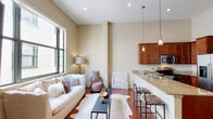 Located in New Orleans, LA, this 1-bedroom, 1-bathroom residence offers a thoughtfully designed open-concept layout that maximizes every square foot. The living area features soaring vaulted ceilings and rich hardwood flooring, creating an airy, welcoming atmosphere. A large picture window floods the space with natural light, while neutral wall tones provide a clean, versatile backdrop throughout.

The kitchen is well-equipped with warm cherry wood cabinetry, granite countertops, and a full suite of stainless steel appliances, including a gas range, microwave, and refrigerator. A peninsula with bar seating connects the kitchen seamlessly to the living area, ideal for casual dining or entertaining. Pendant lighting above the peninsula adds a refined touch.

The bedroom is a calm retreat, highlighted by a generous window that brings in natural light and views of the surrounding urban architecture. Hardwood floors continue into this room, maintaining consistency throughout the unit. A walk-in closet provides ample storage.

The bathroom features tile flooring, a granite-topped vanity with a white undermount sink, brushed nickel fixtures, and a full tub-shower combination with tile surround. Pendant lighting and a large mirror enhance the sense of space. The unit also includes a walk-in closet conveniently accessible from the main living area.
