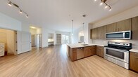 Located at 4150 Ashford Dunwoody Rd NE in Brookhaven, GA, this well-appointed 2-bedroom, 2-bathroom residence offers a thoughtfully designed single-level floor plan. The open-concept kitchen and living area serves as the heart of the home, featuring warm wood-tone cabinetry, a subway tile backsplash, stainless steel appliances including a refrigerator with ice maker, electric range, and built-in microwave. A peninsula island with a white quartz countertop and undermount sink provides additional prep space and seating. Pendant lighting and track lighting illuminate the kitchen, while light wood-style flooring flows seamlessly throughout the main living areas. The spacious living room includes a built-in shelving unit and a dedicated built-in desk nook, with sliding glass doors opening to a private balcony. Both bedrooms are generously sized, featuring ceiling fans, large windows with natural light, and access to walk-in closets outfitted with wire shelving systems. The bathrooms are finished with wood-tone vanity cabinetry, framed mirrors, and glass-enclosed showers. A dedicated in-unit laundry room houses a full-size front-loading washer and dryer with overhead wire shelving for added storage. Light, neutral tones throughout create a clean and contemporary ambiance.