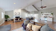 Located at 314 Great Lakes Dr in Noblesville, Indiana, this single-floor space offers an open-concept layout that seamlessly integrates a living room, dining area, and kitchen. The most striking architectural feature is the dramatic vaulted ceiling, which soars overhead and lends a grand sense of volume throughout the main area. Warm hardwood flooring runs continuously underfoot, unifying the space with a cohesive, inviting feel.

The living area is anchored by a classic brick fireplace with a clean white finish, serving as a focal point beneath the high ceiling. Ceiling fans provide both function and style, complementing the abundant natural light that pours in through multiple windows. A comfortable seating arrangement and designated dining space with a wood table and leather chairs make the layout highly functional.

A standout feature is the built-in coffee bar station, complete with white cabinetry, granite-style countertops, open shelving, and a beverage refrigerator — an ideal amenity for a shared or community space. The kitchen features white shaker cabinets, granite-look countertops, and a large window that fills the room with natural light. An elegant arched entryway adds a refined architectural detail, while the neutral gray walls throughout create a calm, modern backdrop that ties every element of the space together.