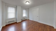 Located on Walnut Street in the heart of Philadelphia, this single-floor unit offers a practical and comfortable layout with consistent design elements throughout. The kitchen is efficiently arranged with white cabinetry, dark granite countertops, a tile backsplash, a gas range, stainless steel sink, and a full-size refrigerator — providing everything needed for everyday cooking. The entry leads through a galley-style kitchen corridor into the main living areas, where rich hardwood flooring flows seamlessly from room to room. Multiple rooms feature large windows with horizontal blinds, allowing generous natural light to fill the spaces. Baseboard heating units are present throughout, ensuring year-round comfort. The living areas are bright and open, with neutral white walls and textured ceilings that lend a clean, understated aesthetic. One room provides direct access to the bathroom, which is finished with large-format tile on both the floors and walls, a soaking tub, a pedestal-style vanity with a dark wood cabinet, and a window for natural ventilation. Clean white trim and neutral tones unify the space, creating a cohesive and move-in-ready environment in one of Philadelphia's most well-known neighborhoods.