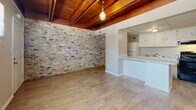 This 510 square foot apartment in Mobile, AL offers a harmonious blend of modern comfort and rustic charm. The single-story layout comprises a living room, one bedroom, a hallway, and a bathroom, making efficient use of the compact space. A standout feature is the exposed wood beam ceiling, adding warmth and character throughout.

The living area is notably spacious, with hardwood flooring that extends through the entire apartment. One wall showcases an eye-catching exposed brick feature, adding texture and visual interest. The open-concept design seamlessly integrates the living space with the kitchen, which is partially visible through a pass-through counter.

The bedroom, measuring 170 square feet, is generously sized for the apartment's overall dimensions. It features the same hardwood flooring and exposed beam ceiling, with a large window allowing ample natural light. The hallway area includes built-in storage solutions, evident from the multiple white doors, likely concealing closets or utility spaces.

The kitchen, while compact, appears modern with white cabinetry and black appliances. Throughout the apartment, the walls are painted in neutral tones, providing a clean, contemporary backdrop that complements the rustic ceiling elements. Pendant lighting fixtures add a touch of modern style, illuminating the space effectively.

This apartment successfully combines functional living with appealing design elements, making the most of its 510 square feet to create a cozy yet stylish urban dwelling.