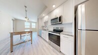 Located at 1216 N Atlantic Ave in Daytona Beach, FL, this one-bedroom, one-bathroom unit offers a well-designed layout with thoughtful finishes throughout. The kitchen is a standout feature, showcasing crisp white shaker cabinetry extending to the ceiling, granite countertops, a classic white subway tile backsplash, and a full suite of stainless steel appliances including an electric range, built-in microwave, and dishwasher. Light wood-style flooring runs through the main living areas, complementing the bright, airy aesthetic. The open kitchen flows naturally toward a windowed living area equipped with a ceiling fan, allowing natural light to fill the space. The bedroom is carpeted for comfort, featuring windows with blinds that bring in natural light and offer exterior views. A dedicated closet provides convenient storage near the entryway. The bathroom is elegantly appointed with large-format marble-style tile lining the walk-in shower surround, paired with a clean white shower base and light flooring. A wall-mounted vanity light adds a refined touch. The overall design is clean and contemporary, with a neutral color palette that creates a cohesive and inviting atmosphere throughout.