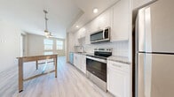 Located at 1216 N Atlantic Ave in Daytona Beach, FL, this one-bedroom, one-bathroom unit offers a well-designed layout with thoughtful finishes throughout. The kitchen is a standout feature, showcasing crisp white shaker cabinetry extending to the ceiling, granite countertops, a classic white subway tile backsplash, and a full suite of stainless steel appliances including an electric range, built-in microwave, and dishwasher. Light wood-style flooring runs through the main living areas, complementing the bright, airy aesthetic. The open kitchen flows naturally toward a windowed living area equipped with a ceiling fan, allowing natural light to fill the space. The bedroom is carpeted for comfort, featuring windows with blinds that bring in natural light and offer exterior views. A dedicated closet provides convenient storage near the entryway. The bathroom is elegantly appointed with large-format marble-style tile lining the walk-in shower surround, paired with a clean white shower base and light flooring. A wall-mounted vanity light adds a refined touch. The overall design is clean and contemporary, with a neutral color palette that creates a cohesive and inviting atmosphere throughout.