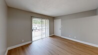 Located at 1200 W Martintown Rd in North Augusta, SC, this well-appointed 2-bedroom, 2-bathroom unit offers a practical and comfortable single-floor layout. Throughout the home, light-toned hardwood-style flooring creates a clean, cohesive aesthetic complemented by neutral gray walls and crisp white trim.

The living room is an inviting, open area anchored by a sliding glass door with vertical blinds that allows natural light to pour in while providing outdoor views of the surrounding greenery. A separate entry door adds convenience to this welcoming space.

The galley-style kitchen is a functional highlight, featuring white shaker cabinetry, granite countertops, a modern stainless steel sink with a flexible faucet, and stainless steel appliances including a refrigerator and range. Ample upper and lower cabinet storage makes this kitchen as practical as it is attractive.

The spacious primary bedroom includes a ceiling fan with light, a window with natural views, and access to a dedicated walk-in closet. The second bedroom is generously sized with its own closet and a sliding glass door. A connecting hallway with a built-in thermostat links the bedrooms to the two full bathrooms, one of which features a clean, all-white tub-shower surround. Textured ceilings are featured in select areas of the home.