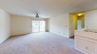 This single-floor residence at 326 Commonwealth Court in Charlottesville, Virginia offers a practical and well-organized layout across a generous footprint. The living area is notably spacious, finished with plush wall-to-wall carpeting and anchored by a ceiling fan that promotes comfortable airflow. A sliding glass door floods the room with natural light and provides direct access to the outdoors, enhancing the open feel of the space. An adjacent area, also carpeted and outfitted with a ceiling fan and chandelier, functions well as a dining or secondary living space, with wainscoting details adding a touch of classic character.

The kitchen features warm-toned wood cabinetry, a white appliance suite including a range and refrigerator, and a peninsula that connects the cooking area to the rest of the living space. Bedrooms are carpeted and bright, with one offering a window with natural views to the exterior. The bathrooms are consistently appointed with rich wood vanities, overhead cabinets for storage, light countertops, and neutral tile flooring, creating a cohesive and functional aesthetic throughout. The overall ambiance is clean, neutral, and move-in ready.