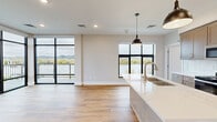 Located in the heart of downtown Winona, MN, this modern 2-bedroom, 2-bathroom residence offers a thoughtfully designed open-concept layout with impressive views of the Mississippi River and surrounding bluffs. The combined kitchen and living area is a true centerpiece, featuring large-format black-framed floor-to-ceiling windows that flood the space with natural light. The kitchen is outfitted with taupe shaker cabinetry, a white quartz waterfall island with an undermount sink, subway tile backsplash, stainless steel appliances, and stylish pendant lighting. Warm-toned hardwood flooring flows throughout the main living areas. A private balcony, accessible via a glass-paneled door, offers panoramic views of downtown Winona and the scenic bluff landscape. The bedrooms are carpeted for comfort, each with generous closet space, including a spacious walk-in closet in the primary suite. The primary bathroom features elegant marble-style tile, a frameless glass sliding shower enclosure, and wood-tone vanity cabinetry. A dedicated laundry room with a full-size washer and dryer adds everyday convenience. Additional features include a pantry, multiple closets, and a second full bathroom, making this a well-appointed and functional urban residence.