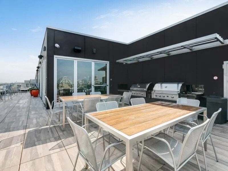 Outdoor rooftop patio with picnic tables and stainless steel grills.