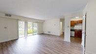 Located near I-95 in Sharon, MA, this single-floor, 1-bedroom, 1-bathroom residence offers a generous 2,160 square feet of living space. The open-concept kitchen and living room serves as the heart of the unit, featuring warm hardwood-style flooring throughout and a bright, neutral color palette. The kitchen is well-appointed with rich wood cabinetry, dark granite-style countertops, stainless steel appliances including a refrigerator, electric range with microwave, and a breakfast bar with a wood countertop. The spacious living area is bathed in natural light through large sliding glass doors that open to views of the lush, tree-lined grounds of the surrounding brick residential complex. The bedroom, spanning 160 square feet, includes a window offering natural light and continues the consistent hardwood-style flooring. The bathroom features a clean, white finish with overhead cabinetry for storage and a tiled tub-shower combination. A staircase provides additional access within the building. The unit's neutral tones, modern fixtures, and ample square footage create a functional and comfortable living environment.