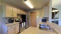 Located in Dublin, Ohio, this two-floor residential property at 6564 Millridge Cir offers a well-organized layout designed for everyday comfort. The main living area features carpeted flooring and is filled with natural light streaming through large windows dressed with light curtains, creating a bright and welcoming atmosphere. The front entry opens directly into this open space, which connects seamlessly to a dedicated dining area — ideal for both casual meals and entertaining. The kitchen is efficiently arranged in a galley-style configuration, featuring stainless steel appliances including an electric range and refrigerator, ample cabinetry providing generous storage, a double stainless steel sink, and a textured ceiling with overhead fluorescent lighting. Light-toned countertops and a neutral color palette give the kitchen a clean, practical feel. An interior door in the kitchen leads to additional areas of the home. The overall aesthetic throughout the space is understated and functional, with warm neutral tones complementing the layout across both floors. The property's location within the established Millridge Circle neighborhood in Dublin, OH offers convenient access to local amenities, schools, and community resources.
