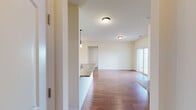This single-story residence is designed with an open, functional layout that promotes a comfortable flow between living spaces. The kitchen serves as a central hub, featuring warm medium-toned wood cabinetry, granite-style countertops, and black appliances including a range, microwave, and refrigerator. A peninsula with a built-in sink extends the counter space and doubles as a casual dining or serving area, illuminated by a pair of stylish pendant lights overhead. The kitchen opens directly into the living area, which is finished with rich wood-style flooring and neutral walls throughout. A sliding glass door in the living space connects to an outdoor balcony, filling the room with natural light and providing exterior views.

The bedrooms are carpeted for comfort and equipped with ceiling fans. Multiple windows bring in abundant natural light, and closet space is included. The bathroom features a full tub-shower combination with a curved curtain rod, granite-style vanity countertop, and wood-style flooring that mirrors the main living areas. A dedicated in-unit laundry area accommodates a full-size washer and dryer, adding everyday convenience to this well-appointed residence.