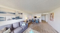 This single-floor residence offers a thoughtfully arranged layout that balances functionality and comfort throughout its living spaces. The open-concept living and dining area serves as the heart of the home, featuring plush carpeting, a textured ceiling, and a striking wall of floor-to-ceiling windows that flood the space with natural light and frame sweeping outdoor views. The seamless flow between the living and dining zones makes the area feel especially spacious and inviting.

The kitchen is well-equipped with dark wood cabinetry, granite-style countertops, a double sink, and a full suite of black appliances including a range, dishwasher, and refrigerator. Wood-look flooring and a window above the sink add practicality and brightness to the workspace. A pass-through opening connects the kitchen to the dining area, enhancing the open feel.

The bedrooms are carpeted and bright, with one room featuring a large window overlooking the outdoors. Each bedroom includes a dedicated closet, offering generous storage. An in-unit laundry area accommodates a full-sized washer and dryer with wire shelving above for additional storage. Throughout the residence, white walls and textured ceilings maintain a clean, neutral aesthetic.