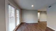 This single-floor residence in Roswell, GA, offers a clean, modern aesthetic defined by neutral gray walls, crisp white trim, and rich wood-look flooring throughout the main living areas. The open living space is bright and welcoming, with large windows dressed in white horizontal blinds that invite generous natural light. French doors provide direct access to the outdoors, enhancing the sense of openness and connectivity to the exterior. The galley-style kitchen is well-appointed with white upper cabinetry, two-toned gray lower cabinets, white countertops, a stainless steel sink, and a full suite of appliances including a refrigerator, range, microwave, and dishwasher. Light wood-look flooring runs underfoot, complementing the crisp, functional layout. The bedrooms feature plush carpeting and windows with outdoor views, creating comfortable, quiet retreats. The primary bedroom includes a walk-in closet, providing ample storage. The bathroom offers wood-look flooring, a dark accent storage cabinet, and a clean, straightforward layout. Throughout the residence, consistent finishes, recessed lighting, and ceiling fans contribute to a cohesive and practical living environment well-suited for everyday comfort.