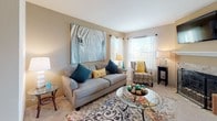 Located at 4801 S Wadsworth Blvd in Denver, Colorado, this single-floor residence offers a thoughtfully designed layout across multiple living spaces. The open living room features neutral carpet, large windows that invite natural light, and warm neutral-toned walls. A dedicated dining area accommodates a full dining set beneath a pendant light fixture, with decorative wall shelving adding character to the space. An additional flexible room with carpet provides space suitable for a home office or sitting area. The galley-style kitchen is equipped with stainless steel appliances including a range, microwave, and refrigerator, complemented by warm wood cabinetry, granite-style countertops, and hardwood flooring. A convenient laundry area is accessible directly from the kitchen. The primary bedroom features plush carpet, a ceiling fan, a closet, and direct access to an en suite bathroom appointed with dual sinks, warm wood cabinetry, a large vanity mirror, and Hollywood-style lighting. A secondary full bathroom includes a tub-shower combination with tile surround and tile flooring. Throughout the residence, a cohesive color palette of warm taupes and neutral tones creates a calm and welcoming ambiance.