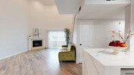 Located in Los Angeles, CA, this two-story, 1-bedroom, 1-bathroom home offers a well-designed layout spread across two floors. The main level opens into a combined living, dining, and kitchen area highlighted by dramatically high ceilings that amplify the sense of space. The living room features wood-look flooring, a fireplace, and a large sliding glass door that floods the area with natural light and provides outdoor views. A staircase leads to an upper loft level, adding versatile bonus space.

The kitchen is a standout, outfitted with a striking waterfall-edge quartz island, matching quartz countertops, white shaker cabinetry, stainless steel appliances, and a skylight that brings in additional natural light. The dining area is distinguished by warm terracotta tile flooring and elegant white columns, lending a Mediterranean-inspired character to the space.

The bedroom is generously sized with crown molding, a ceiling fan, a window with outdoor views, and a full-wall mirrored sliding-door closet. The bathroom features a soaking tub with travertine tile surround. Additional highlights include a dedicated laundry room and hallway. Wood-look flooring runs throughout the main living areas, tying the design together cohesively.