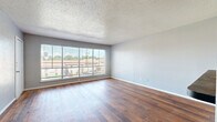 Located at 4503 Lake Ave in Dallas, TX 75219, this one-bedroom, one-bathroom unit offers a practical and comfortable layout across a single floor. The entry opens into a well-proportioned living room highlighted by a wide, multi-pane window that floods the space with natural light and frames views of the surrounding neighborhood. Rich hardwood-style flooring runs throughout the main living areas, complementing the neutral gray walls and textured ceilings.

The galley-style kitchen is efficiently arranged with gray cabinetry, dark countertops, a double sink, and full-size appliances including a stainless refrigerator and range. A peninsula counter extends the workspace and provides a natural transition between the kitchen and living areas.

The bedroom is a well-sized, carpeted retreat with its own window that brings in natural light and outdoor views. Two closets offer ample storage throughout the unit. The full bathroom features wood-style flooring, a vanity with countertop storage, and a bathtub-shower combination.

The overall aesthetic is clean and functional, with consistent neutral tones and durable finishes throughout. The layout flows logically from the entrance through the living and kitchen areas to the private bedroom and bath, making efficient use of the available space.