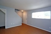 Located at 827 41st Street in Newport News, Virginia, this two-story home offers a practical and well-organized layout across both floors. The interior is finished with cool gray walls and crisp white trim throughout, creating a clean, neutral palette that complements a variety of décor styles.

The main level features a spacious living area with warm, honey-toned hardwood-style flooring and a staircase leading to the upper level. Natural light filters in through windows fitted with blinds, adding brightness to the open layout. The kitchen is outfitted with dark espresso cabinetry, granite-style countertops, a tile backsplash, and black appliances including a refrigerator, dishwasher, and range, providing a functional and cohesive workspace.

The bedrooms are distributed across both floors and share a consistent design with hardwood-style flooring in rich light or dark tones, gray walls, and individual closets with rod storage. Windows in several bedrooms allow for natural light and outdoor views. The bathroom includes a full tub-shower combination with white tile surround, a window for ventilation, and a safety grab bar, set atop light-toned flooring. The overall ambiance of the home is straightforward, clean, and move-in ready.
