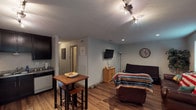 This single-floor, two-bedroom, one-and-a-half-bath unit delivers a practical and well-appointed living experience. The open-concept living and dining area features durable wood-look flooring, recessed and track lighting, and a wall-mounted TV, creating a versatile space suited for both relaxing and entertaining. A compact dining table with bar-height seating sits adjacent to the kitchen, offering a convenient eat-in option.

The kitchen is a standout feature, outfitted with dark espresso cabinetry that extends to the ceiling for ample storage, granite-style countertops, and a full suite of stainless steel appliances including an electric range, over-the-range microwave, refrigerator, and dishwasher.

The bedrooms provide comfortable retreats, with one featuring sliding glass doors that open to an outdoor patio and natural light. Both bathrooms echo the kitchen's design aesthetic with dark cabinetry and granite-style countertops; the full bath includes a shower-tub combo. Wood-look flooring runs through the main living areas, while carpet adds warmth to the bedroom. The unit's neutral color palette and consistent finishes create a cohesive, move-in-ready environment throughout.