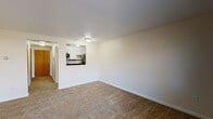 Located at 1459 VFW Pkwy in the West Roxbury neighborhood of Boston, MA, this single-floor unit offers a well-organized layout with functional living spaces throughout. The open living area is finished with neutral wall-to-wall carpeting and crisp white walls, creating a bright and inviting atmosphere. A pass-through window connects the living space directly to the kitchen, enhancing the open feel of the floor plan. The kitchen is well-appointed with white shaker-style cabinetry, dark granite countertops, a classic subway tile backsplash, and a full suite of stainless steel appliances including an electric range, over-the-range microwave, and refrigerator. The bedroom is generously sized, also carpeted, and features a wide window that allows natural light to filter in along with views of the surrounding outdoor landscape. A wall-unit air conditioner and baseboard heating provide year-round climate control. The bathroom features a full tub-shower combination with white tile surround, a distinctive light blue tub, mosaic tile flooring in coordinating tones, a vanity with medicine cabinet, and classic wood-panel doors that add a warm, timeless character to the space.