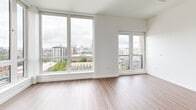 Located on the 14th floor at 535 NW 11th Ave in Portland's vibrant Pearl District, this one-bedroom, one-bathroom unit offers a thoughtfully designed open-concept layout with modern finishes and impressive city views. The combined kitchen and living area is anchored by expansive floor-to-ceiling windows that flood the space with natural light and frame sweeping panoramic views of the Portland skyline. A private balcony extends the living area outdoors, enhancing the sense of openness. The living area features smooth hardwood-style flooring that flows seamlessly throughout the main space. The kitchen is well-appointed with a clean two-tone cabinetry design—pairing white upper cabinets with warm wood-grain lower cabinets—complemented by light quartz countertops and a full suite of stainless steel appliances, including a French door refrigerator, range, dishwasher, and built-in microwave. The bedroom is carpeted and filled with natural light from a large window, offering a quiet retreat from the main living area. A dedicated closet provides organized storage. The bathroom features a full soaking tub and shower combination with clean white tile surround and polished chrome fixtures, maintaining the unit's crisp, contemporary aesthetic throughout.