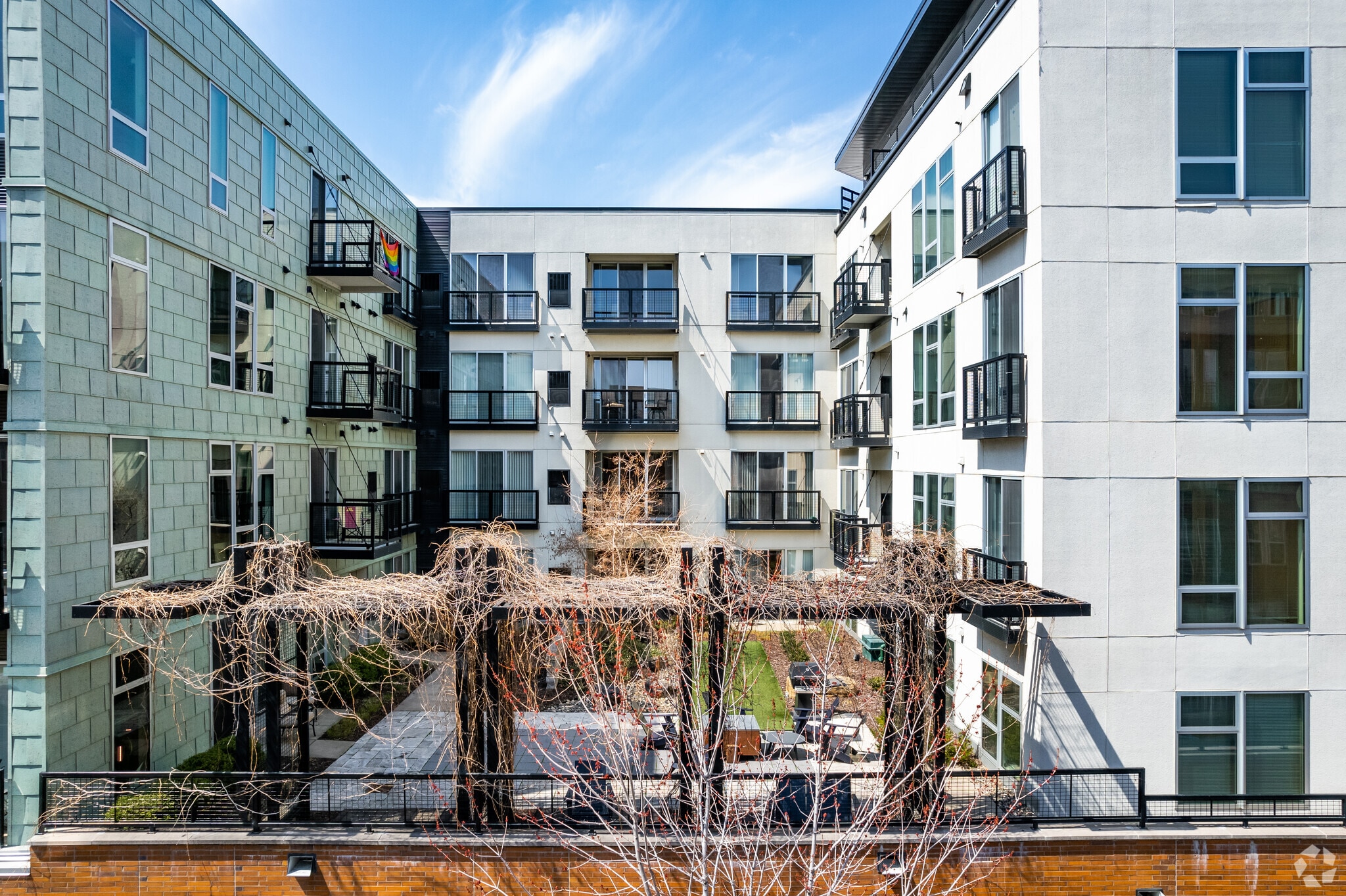 Courtyard of a modern apartment building with balconies and a seating area.