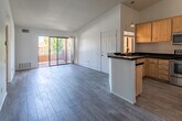 Located at 78650 Avenue 42 in Bermuda Dunes, California, this single-floor unit offers a clean, functional layout finished with consistent wood-look flooring throughout every room. The open living area is bright and airy, benefiting from vaulted ceilings and a large sliding glass door that leads to a private balcony with outdoor views of the surrounding landscape. A ceiling fan adds comfort to this central living space, which flows naturally into the kitchen via a peninsula-style breakfast bar. The kitchen is well-appointed with warm oak cabinetry, dark countertops, and a full suite of stainless steel appliances including a refrigerator, range, and microwave. A window above the sink brings in additional natural light. The bedrooms are generously sized with high ceilings and large windows that invite abundant sunlight. Each bedroom includes dedicated closet space with built-in shelving and hanging rods. The bathroom features a tub-shower combination enclosed by sliding glass doors, complemented by wood-look flooring that ties the space together cohesively. Throughout the unit, the neutral white walls and light flooring create a bright, versatile ambiance well-suited to the warm Southern California desert setting.