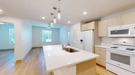 Located at 2012 N Orange Ave in Sarasota, Florida, this single-floor, 2-bedroom, 2-bathroom residence offers a clean, modern aesthetic throughout. Light hardwood flooring flows continuously across the living areas and bedrooms, creating a bright and cohesive feel. Ceiling fans are installed in each bedroom, complementing the natural light that enters through horizontal-slatted windows with outdoor greenery views.

The kitchen is a functional centerpiece, featuring light wood cabinetry with ample storage, white appliances including a range, over-the-range microwave, and refrigerator, along with a white quartz peninsula with an undermount sink and pendant lighting overhead — ideal for both meal prep and casual dining.

Both bedrooms are well-proportioned, with the primary bedroom offering a generous layout and direct access to adjoining rooms. Each bedroom features clean white walls, ceiling fans, and windows that bring in natural light.

The two bathrooms are designed with accessibility in mind. One features a walk-in shower with grab bars and a light wood vanity with white countertop. The second includes a full soaking tub with grab bars and a matching vanity. Both bathrooms are finished with large-format tile flooring for a polished, modern look.