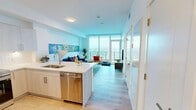 Located in Calgary's SW community, this bright and modern one-bedroom, one-bathroom unit offers a well-designed open-concept layout with light hardwood flooring throughout. The kitchen is a standout feature, equipped with sleek light-wood cabinetry, white quartz countertops, a full suite of stainless steel appliances, subway tile backsplash, and a generously sized island with bar seating — ideal for both cooking and entertaining. The kitchen flows seamlessly into the living area, where floor-to-ceiling windows flood the space with natural light and frame expansive panoramic views of the Calgary skyline and surrounding cityscape. Access to a private balcony extends the living space outdoors. The bedroom is a serene retreat, featuring large windows with sweeping city views, light hardwood floors, and a spacious walk-in closet outfitted with wire shelving for ample storage. The bathroom is clean and contemporary, appointed with a wide vanity, quartz countertop, and a glass-enclosed walk-in shower with a rainfall showerhead. Crisp white walls and an abundance of natural light create a bright, airy ambiance throughout the entire unit, making it a compelling high-rise residence in the heart of Calgary.