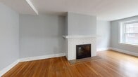 This charming apartment, located at 703 West Ferry Street in Buffalo, New York, offers a blend of classic and modern features across its 1120 square feet. The space is efficiently laid out with two bedrooms, one bathroom, and multiple living areas spread across a single floor.

Upon entering, you're greeted by gleaming hardwood floors that run throughout the apartment, adding warmth and character. The living spaces are bathed in natural light, thanks to large, double-hung windows with elegant white trim. These windows not only brighten the rooms but also offer views of the surrounding neighborhood.

A standout feature is the beautifully crafted brick fireplace with a white mantel, serving as a focal point in one of the living areas. This element adds both visual interest and a cozy ambiance to the space.

The kitchen, while compact, is functional and updated with cherry-wood cabinets and modern appliances, including an electric stove. The bathroom features classic white tiling and a combination tub-shower unit, maintaining a clean and timeless look.

The bedrooms are generously sized, with the primary bedroom measuring 200 square feet. Each room offers ample closet space and continues the theme of abundant natural light.

The apartment's layout includes two hallways, enhancing the flow between rooms and providing additional utility space. The pale grey walls throughout create a neutral backdrop, allowing for personalization while maintaining a bright, airy feel.

Unique architectural details like baseboards and door frames add character to the space, while modern amenities ensure comfort and convenience. This apartment successfully combines the charm of a classic Buffalo residence with the comforts of contemporary living.