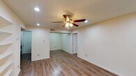 This single-floor unit is designed with a clean, functional layout that connects living, sleeping, and utility spaces efficiently. Wood-look plank flooring runs consistently throughout, lending a cohesive and contemporary feel to every room. Ceiling fans with integrated light fixtures are installed across multiple rooms, providing both comfort and ambient lighting.

The living area serves as the central hub of the unit, highlighted by recessed lighting, a built-in shelving unit ideal for display or storage, and direct access to the rest of the home. Natural light filters in through blinded windows in the bedrooms, each of which offers ample open floor space and its own ceiling fan.

The galley-style kitchen is outfitted with dark espresso cabinetry, granite-look countertops, a double basin sink, and black appliances including a refrigerator and range, making efficient use of the available space.

Two bathrooms mirror each other in design, each featuring wood-look flooring, a tub-shower combination with full tile surround, a toilet, and a vanity with granite-look countertops and dark cabinetry. The overall palette of neutral whites and warm wood tones creates a consistent, move-in-ready ambiance throughout.