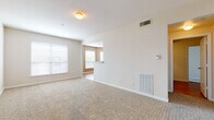 This single-story, 3-bedroom, 2-bathroom residence delivers a comfortable and functional layout designed for everyday living. The spacious living area features plush wall-to-wall carpeting, neutral beige tones, and bright windows with blinds that allow natural light to fill the room. An open sightline connects the living space to the kitchen, which is appointed with white shaker-style cabinetry, granite-look countertops, dark hardwood-style flooring, and stainless steel appliances including a dishwasher and electric range, complemented by a warm accent wall color.

Each bedroom is generously sized with soft carpeting, ceiling fans with integrated lighting, and windows that bring in natural light. The primary bedroom includes access to a walk-in closet fitted with wire shelving racks, providing ample storage. The additional bedrooms offer comfortable proportions with views of the surrounding area.

Both bathrooms feature white cabinetry, granite-look countertops, and dark hardwood-style flooring. One bathroom includes a full tub-shower combination with white tile surround, while both offer practical fixtures and clean, neutral finishes. The overall design of the residence emphasizes a bright, move-in-ready aesthetic with consistent finishes throughout.