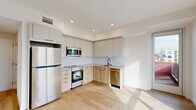 Located at 738 S Normandie Ave in Los Angeles, this thoughtfully designed one-bedroom, one-bathroom unit offers a clean, modern aesthetic with an efficient and functional layout. Light wood-tone flooring runs throughout, complementing the bright white walls and recessed lighting that create a fresh, airy atmosphere.

The open-plan kitchen and living area serves as the heart of the unit. The kitchen is outfitted with stainless steel appliances — including a refrigerator, electric range, built-in microwave, and dishwasher — paired with two-tone cabinetry featuring white upper cabinets and warm wood-grain lower cabinets. A herringbone tile backsplash and light countertops complete the contemporary look. The adjacent living area benefits from abundant natural light.

The bedroom is a serene retreat with a large floor-to-ceiling window offering views of the surrounding Los Angeles neighborhood, light hardwood flooring, and a sliding closet. The bathroom features a classic black-and-white hexagonal tile floor, a full soaking tub with marble-style surround, and matte black fixtures for a stylish contrast.

A dedicated in-unit laundry closet with stacked washer and dryer adds everyday convenience, while a private balcony provides an outdoor retreat with city views.