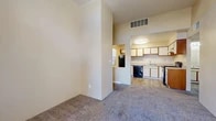 Located at 900 Country Club Dr SE in Rio Rancho, New Mexico, this one-bedroom, two-bathroom residence offers a practical and well-organized single-floor layout. The open-concept living and kitchen area serves as the heart of the home, where warm neutral tones and a combination of wood-look flooring and plush carpeting create a comfortable atmosphere. The kitchen is equipped with white cabinetry accented by wood-tone trim, black appliances including a refrigerator, gas range, and dishwasher, a double sink, and ample counter space. Natural light filters in through a window with blinds, keeping the space bright and airy. The living room flows naturally from the kitchen, offering a cozy carpeted area with elevated ceilings that lend a sense of openness. The bedroom features soft carpet flooring, a window with outdoor views, and generous closet access. Two bathrooms serve the home — one featuring a full tub-shower combination with tiled surround, and the other with a wide vanity, wood-accented cabinetry, a large mirror, and wood-look flooring. A dedicated utility room and hallway complete the efficient floor plan, making this a well-appointed and functional living space.