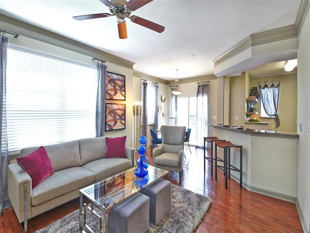 Living room with large window, wood-style flooring and ceiling fan - Aspire Roxbury