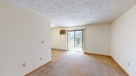 This compact 2-bedroom, 1-bathroom unit is thoughtfully laid out across a single floor, offering a functional and efficient use of space. The living area is carpeted and bathed in natural light through a large sliding glass door fitted with vertical blinds, which opens to an outdoor view and is complemented by a wall-mounted air conditioning unit and baseboard heating. The textured ceiling adds a classic touch to the open feel of this shared living space.

The galley-style kitchen features white cabinetry, a double stainless steel sink, a white electric range with overhead exhaust, and a tiled backsplash. Stone-patterned tile flooring ties the space together for easy maintenance.

Both bedrooms are carpeted and finished with neutral walls and wood baseboards. The primary bedroom is generously sized, while the second bedroom offers a comfortable, cozy footprint. Each room is equipped with baseboard heating, and the second bedroom includes a window with a blind for natural light and privacy.

The bathroom is accessible and well-appointed, featuring grab bars, tile flooring, and a clean, open layout. A dedicated closet provides additional storage. Throughout the unit, the design prioritizes practicality, with consistent finishes and efficient use of every square foot.