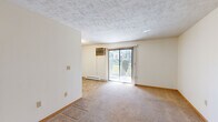 This compact 2-bedroom, 1-bathroom unit is thoughtfully laid out across a single floor, offering a functional and efficient use of space. The living area is carpeted and bathed in natural light through a large sliding glass door fitted with vertical blinds, which opens to an outdoor view and is complemented by a wall-mounted air conditioning unit and baseboard heating. The textured ceiling adds a classic touch to the open feel of this shared living space.

The galley-style kitchen features white cabinetry, a double stainless steel sink, a white electric range with overhead exhaust, and a tiled backsplash. Stone-patterned tile flooring ties the space together for easy maintenance.

Both bedrooms are carpeted and finished with neutral walls and wood baseboards. The primary bedroom is generously sized, while the second bedroom offers a comfortable, cozy footprint. Each room is equipped with baseboard heating, and the second bedroom includes a window with a blind for natural light and privacy.

The bathroom is accessible and well-appointed, featuring grab bars, tile flooring, and a clean, open layout. A dedicated closet provides additional storage. Throughout the unit, the design prioritizes practicality, with consistent finishes and efficient use of every square foot.