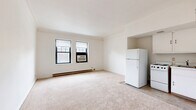 Located at 12506 Edgewater Dr in Lakewood, Ohio, this one-bedroom, one-bathroom unit offers a well-organized, efficient layout across a single floor. The living area is bright and open, featuring neutral carpet flooring, white walls, and multiple windows that invite natural light and views of the surrounding neighborhood. Baseboard heating runs along the perimeter, and a wall air conditioning unit ensures year-round comfort. The kitchen is situated adjacent to the living space and is equipped with a refrigerator and range, providing a functional setup within a compact footprint. The generously proportioned bedroom offers ample room for furnishings and is complemented by a dedicated walk-in closet with built-in shelving, providing excellent storage. The bathroom is a standout feature, showcasing classic white subway tile with black accent detailing, a mosaic hex-tile floor, a soaking bathtub with chrome fixtures, a wood-cabinet vanity, and a lighted medicine cabinet mirror — a nod to timeless design. An entrance area provides a defined transition into the unit. Throughout, the clean white palette and carpeted floors create a calm, cohesive ambiance well-suited for comfortable everyday living.
